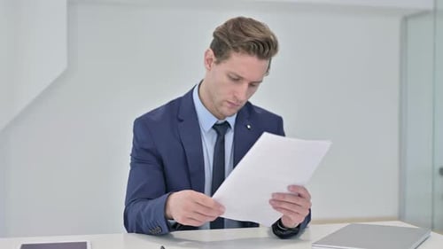 Man Celebrates Reviewing Paperwork in Bright Office