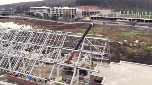 Aerial Shot Installation of a Roof and a Framework From a Metal Construction, Workers Mount the Roof