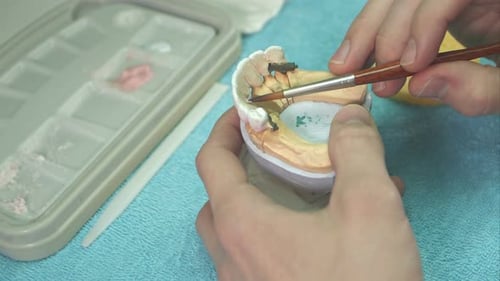 Hands Applying Material to Dental Mold with Brush
