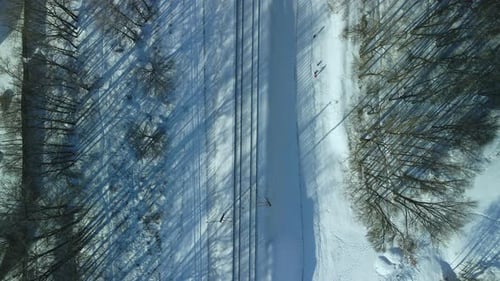 Flug über die Eisenbahn. Ein Zug fährt entlang der Schienen. Winterliche Industrielandschaft.