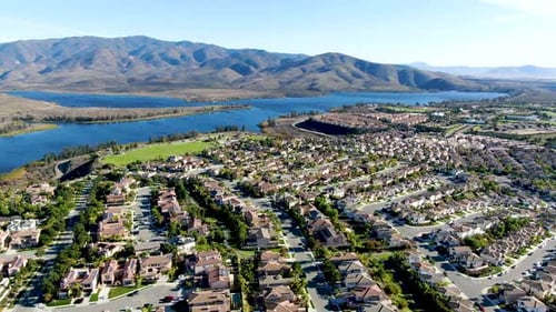 Vista aérea de una casa de subdivisión residencial idéntica con un gran lago y una montaña en el fondo