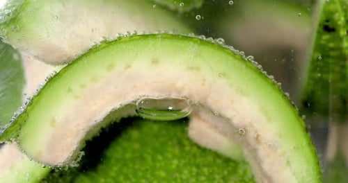 Fresh Slices Avocado Under Water with Air Bubbles.