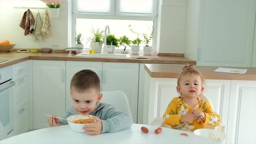 Children Eating Spaghetti at the Kitchen Table