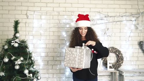 Woman Opening Christmas Gift by Decorated Tree
