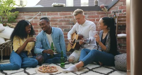 Friends Gather on Rooftop Patio with Guitar and Pizza