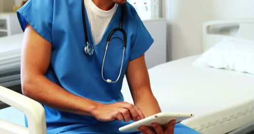 Smiling Doctor Using Tablet in Hospital Room