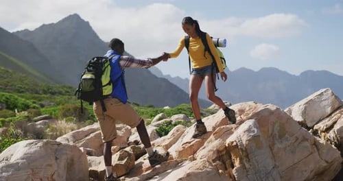 African american couple walking on the rocks while trekking