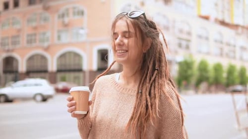 Smiling Woman with Dreadlocks Holding Coffee