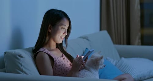 Woman Using Mobile Phone with Dog on Sofa