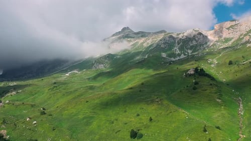 Aerial View of Stunning Mountain Landscape Under Soaring Clouds, Casting Shadow on Green Valley of