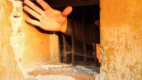 Bettelnde Hand durch Bars