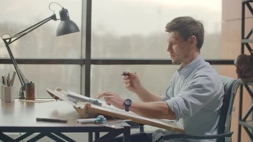Young Man Drawing Draft at Architect Desk