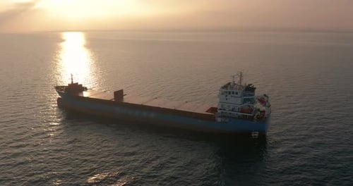 Aerial View. Beatiful Sunset at the Sea. Huge Cargo Ship Floating in the Sea.