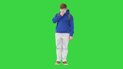 Cool Teenager Boy in Casual Clothes Wearing Medical Mask on a Green Screen, Chroma Key.