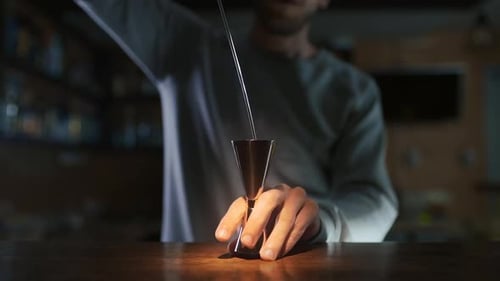 Male Bartender Adding Spoon to a Glass of Liquor