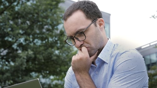 Pensive Man Working on Laptop Outdoors