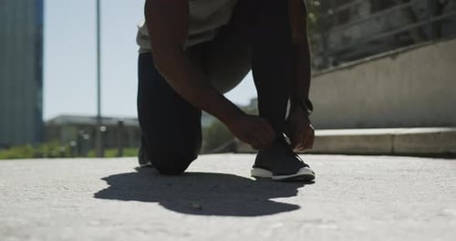 Man Tying Running Shoe in Urban Setting