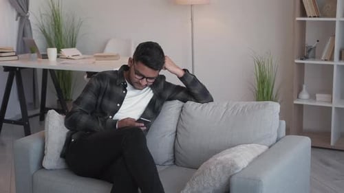 Young Adult Using Smartphone on Couch Indoors