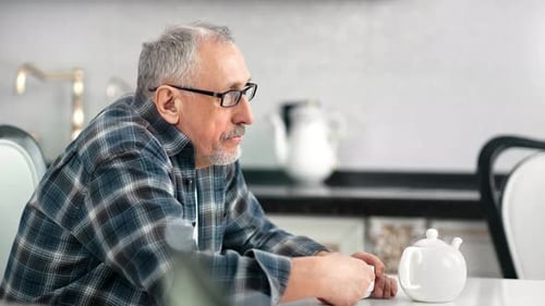Lonely Pensive Aging Male Drinking Tea at White Kitchen Having Calmness Emotion Medium Closeup