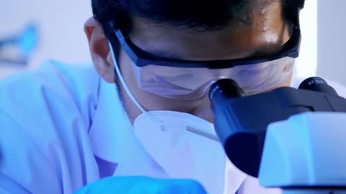 Scientist Looks Through Microscope in Brightly Lit Lab