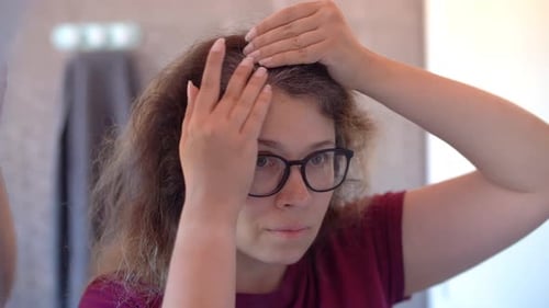 Woman Checks Her Gray Hair in Mirror