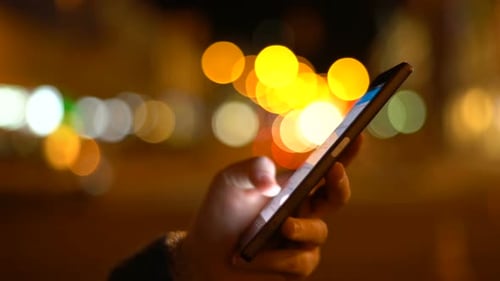 Hand Using Smartphone at Night in City