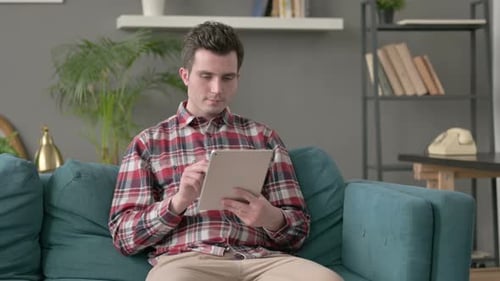 Man Using Tablet on Couch at Home
