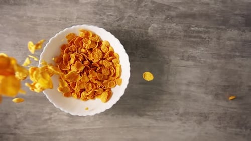 Golden Corn Flakes Pouring Into White Bowl