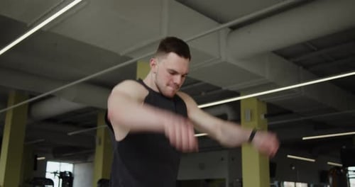 Young Muscular Athlete Works Out in a Modern Gym Making Warmup Exercises