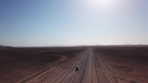 Car Driving on Gravel Road in Aerial Desert