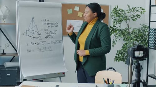 Math Teacher Explains Formulas Next to Whiteboard