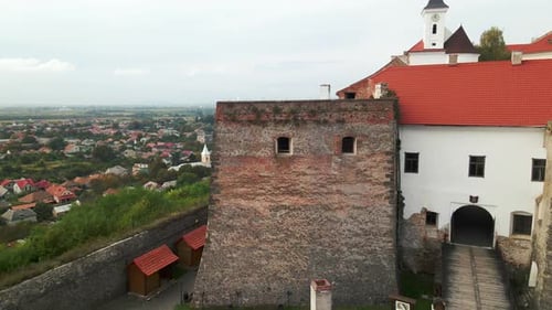 Drone Flies Over Medieval Castle on Mountain in Small European City at Cloudy Autumn Day