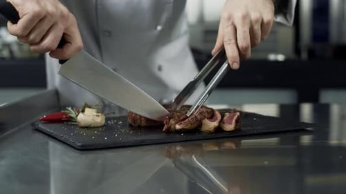 Chef Hands Cutting Steak at Kitchen Restaurant. Closeup Chef Slicing Meat