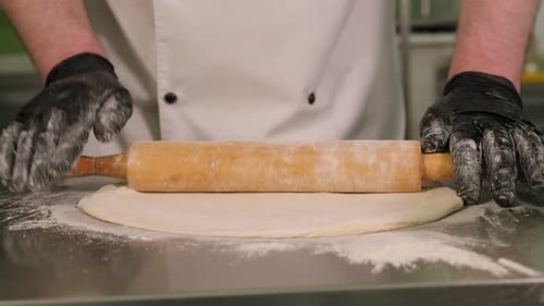 Adult Rolling Dough with Pin on Stainless Steel Surface