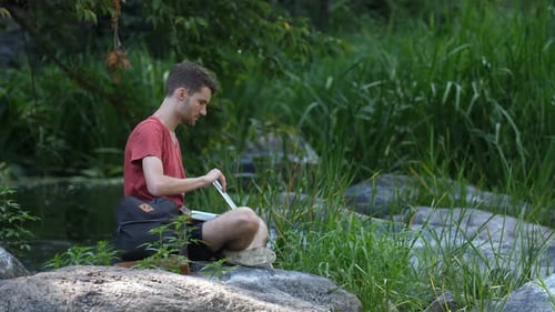 Young Man Using Laptop in Forest Setting