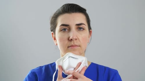 Woman Putting on a White Respirator Mask