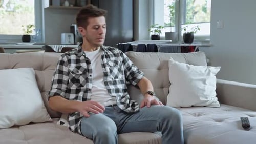 Man Relaxes on Couch, Watches Television