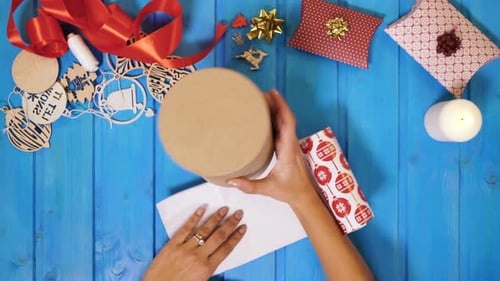 Wrapping Christmas Gift on Blue Wood Table