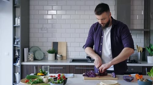 Man Slicing Red Cabbage in Kitchen