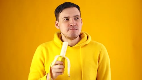 Man Eating a Banana on Yellow Background