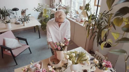 High Angle View of Female Florist Preparing Composition at Table in Flower Shop