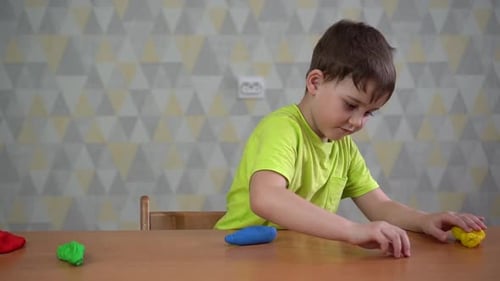 Boy plays with modeling clay at table