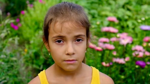 Young Girl Wipes Nose in a Flower Garden