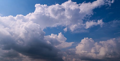 Fluffy White Clouds Drifting Across Blue Sky
