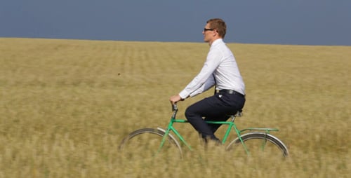 Man Riding Bicycle Through a Wheat Field