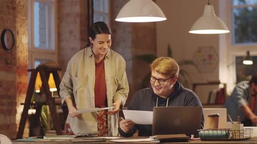 Two Colleagues Discussing Papers in Loft Office