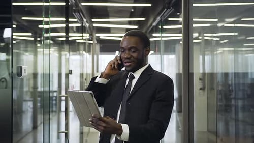 Young Adult Businessman Talking on Phone, Holding Tablet