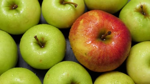 Ein roter und viele grüne Äpfel rotieren