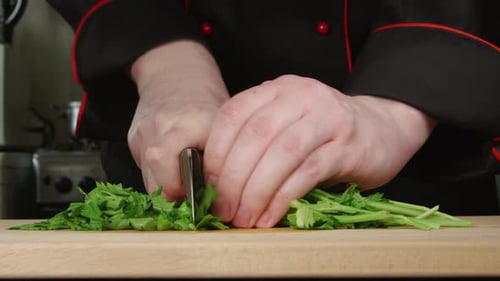 A Cook Cuts A Parsley On A Cutting Board In A Kitchen