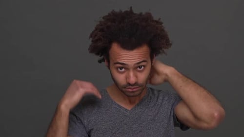 Man Fanning Himself Against Gray Background